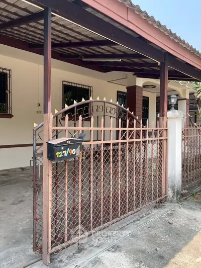 Charming residential entrance with gated fence and covered porch, ideal for privacy and security.