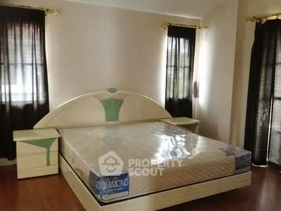 Spacious bedroom with elegant bed and natural light through large windows.