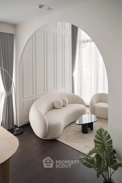 Elegant modern living room with curved sofa, chic decor, and large windows for natural light.