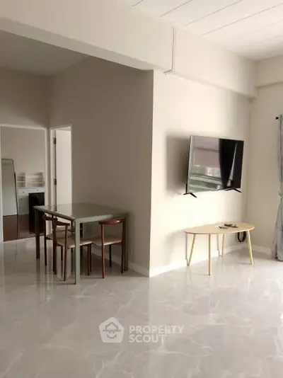 Modern living room with sleek marble flooring and wall-mounted TV, featuring a dining area with stylish furniture.