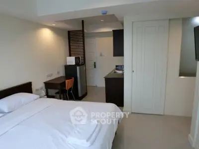 Modern studio apartment with cozy bedroom and compact kitchen area.