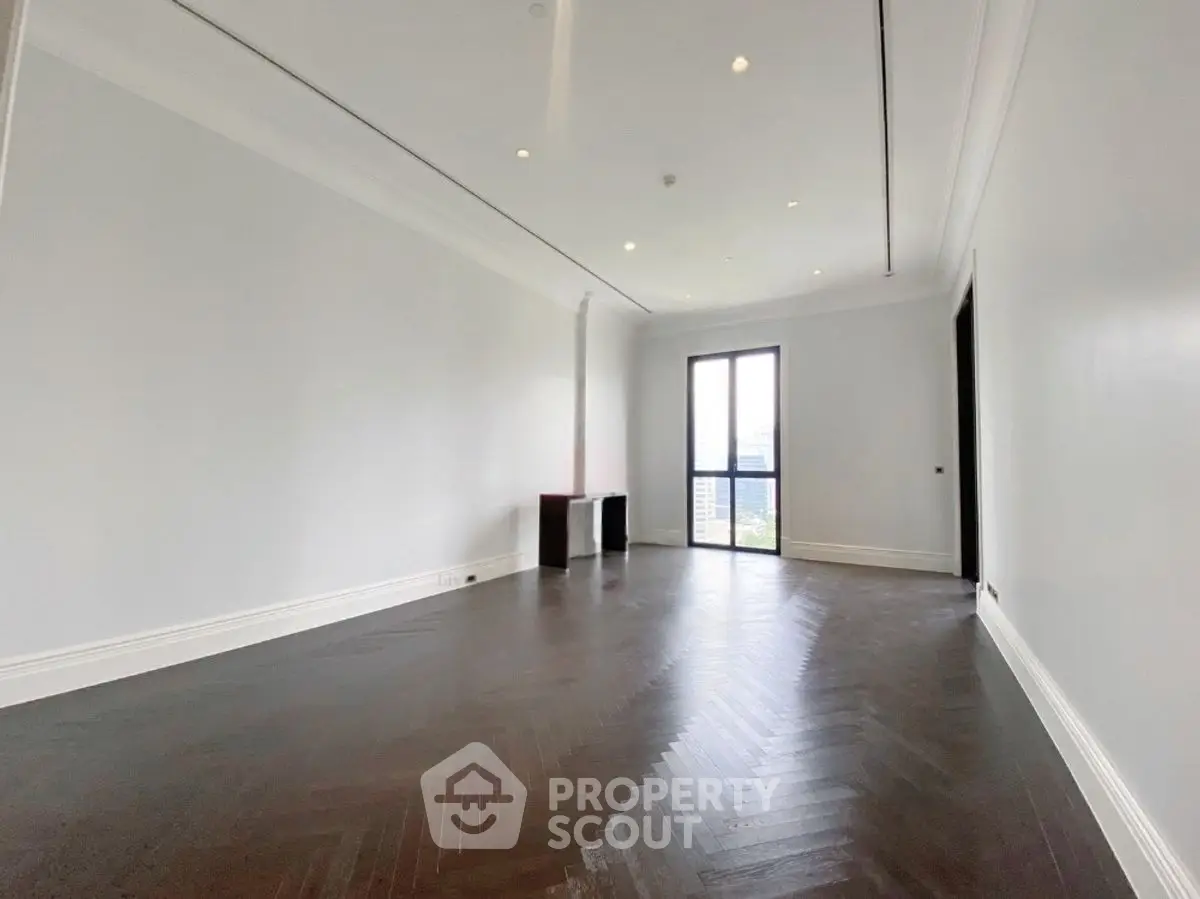 Spacious empty living room with dark wood flooring and large window view.