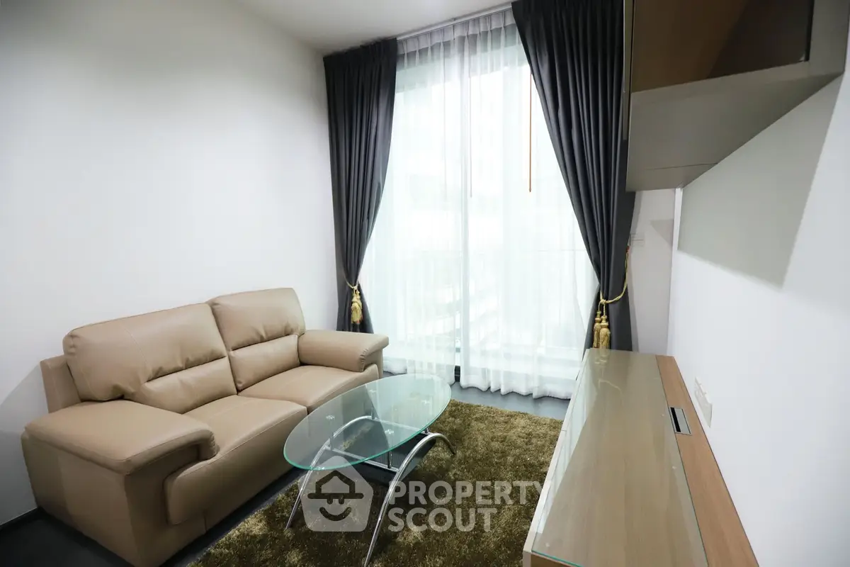 Modern living room with leather sofa and glass coffee table, featuring floor-to-ceiling windows and elegant curtains.