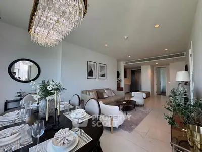 Luxurious open-plan living and dining area with elegant chandelier and modern decor.