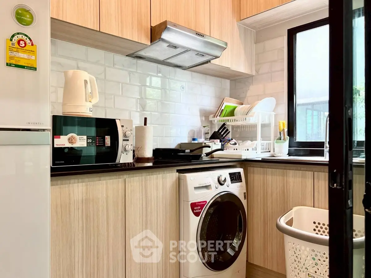 Modern kitchen with washing machine, microwave, and sleek cabinetry