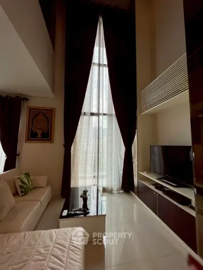 Luxurious high-ceiling living room with elegant decor and large windows.