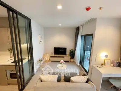 Modern living room with open kitchen and balcony access, featuring cozy seating and stylish decor.