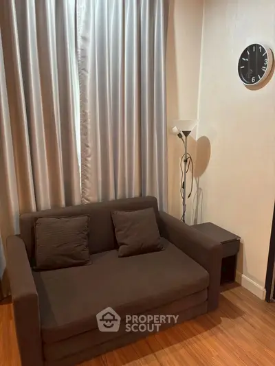 Cozy living room with dark sofa, elegant curtains, and modern floor lamp.
