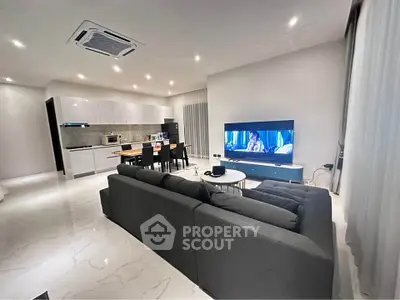 Spacious modern living room with open kitchen, sleek furniture, and ambient lighting for a cozy atmosphere.