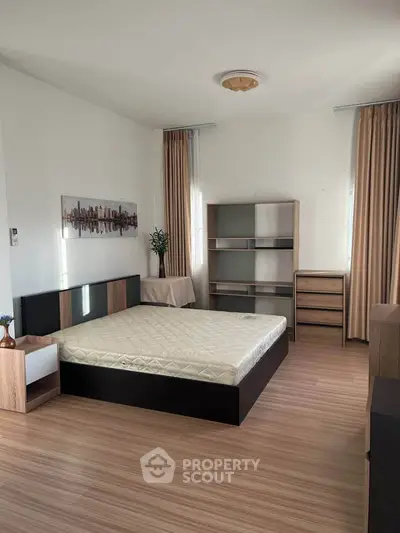 Spacious bedroom with modern furniture and natural light, perfect for comfortable living.