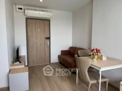 Modern living room with wooden flooring, compact sofa, and dining table in cozy apartment.