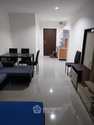 Modern apartment interior with sleek furniture and open layout, featuring a cozy dining area and compact kitchen.