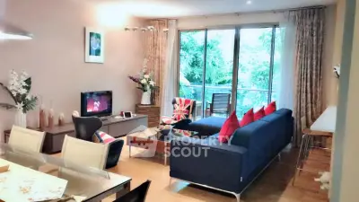 Stylish living room with modern decor and large windows overlooking lush greenery.