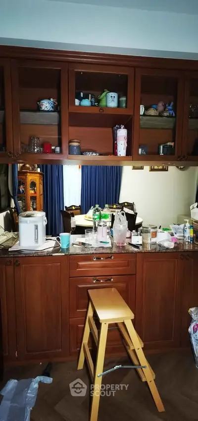 Charming kitchen with wooden cabinets and open layout, featuring a cozy dining area in the background.