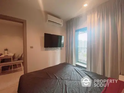 Modern bedroom with balcony view and wall-mounted TV in a stylish apartment.