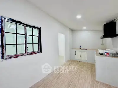Modern kitchen with sleek design and ample natural light, featuring tiled flooring and a minimalist aesthetic.