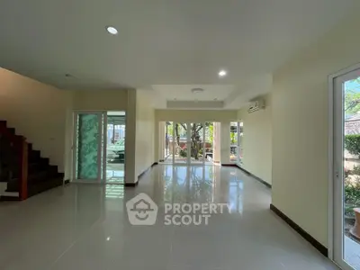 Spacious living room with large windows and garden view, perfect for family gatherings.