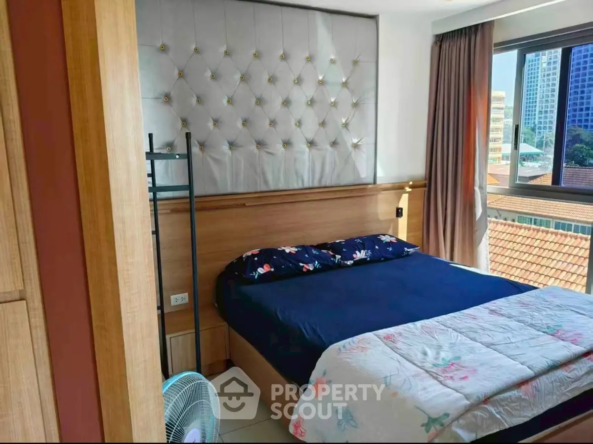 Cozy bedroom with elegant headboard and large window offering city views