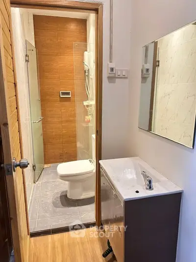 Modern bathroom with sleek fixtures and wooden accents, featuring a glass-enclosed shower and stylish vanity.