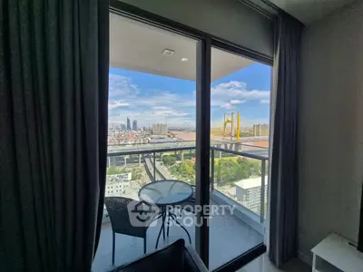 Stunning city view from modern apartment balcony with cozy seating area.