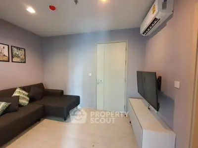 Modern living room with sleek furniture and wall-mounted TV in a cozy apartment.