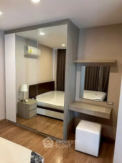 Modern bedroom with mirrored wardrobe and stylish vanity in a cozy apartment.