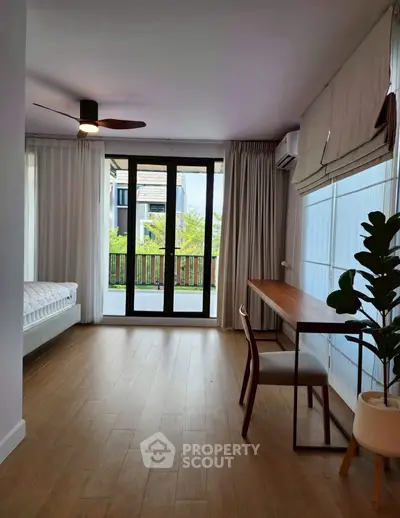 Spacious modern room with wooden flooring, large windows, and stylish furniture, perfect for a serene living experience.