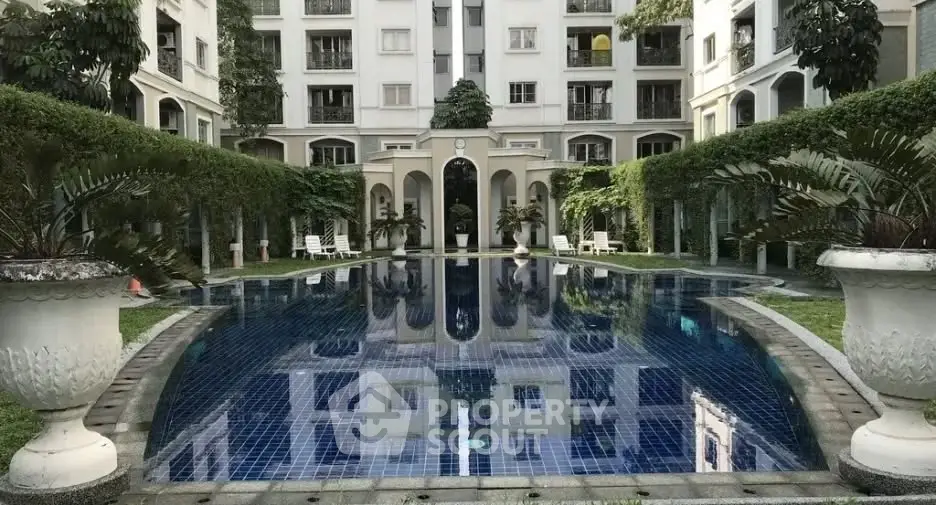 Luxurious apartment complex with serene pool and lush greenery