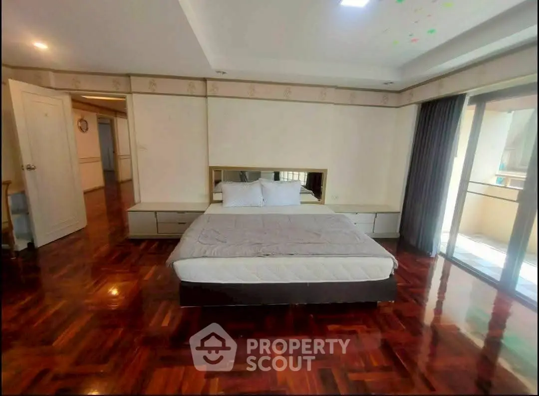 Spacious bedroom with hardwood floors and balcony access in a modern apartment.