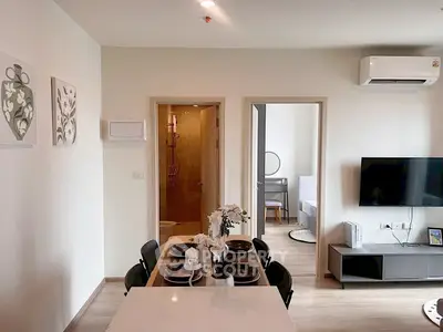 Modern apartment interior with dining area, wall-mounted TV, and air conditioning.