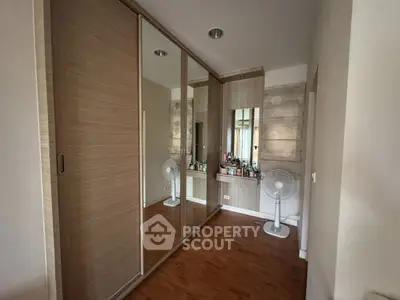 Spacious bedroom with mirrored wardrobe and wooden flooring