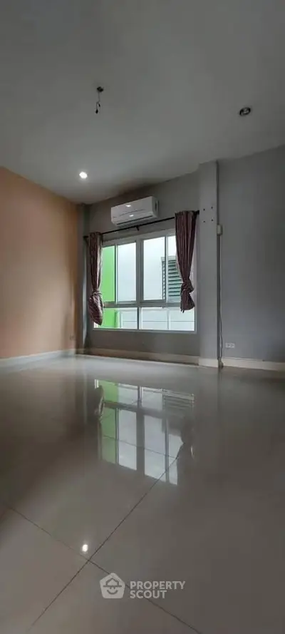 Spacious empty room with large window and air conditioning unit