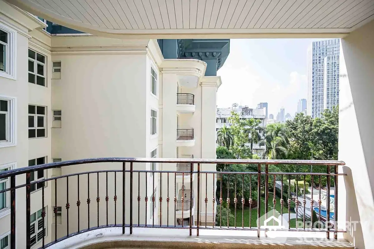 Spacious balcony with wrought iron railing, offering a serene view of lush greenery and neighboring residential architecture, perfect for outdoor relaxation.