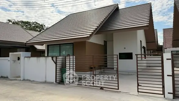 Charming modern house with sleek roof design and gated driveway in a serene neighborhood.