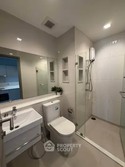 Modern bathroom with glass shower and sleek fixtures in contemporary apartment.