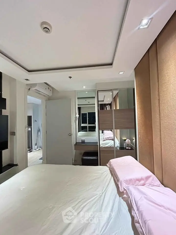 Modern bedroom with stylish decor and mirrored wardrobe in a cozy apartment.