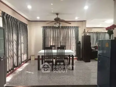 Spacious dining area with elegant curtains and ceiling fan in a cozy home setting.