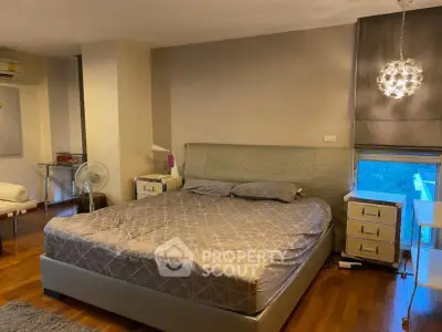 Spacious bedroom with modern decor and large window offering natural light.