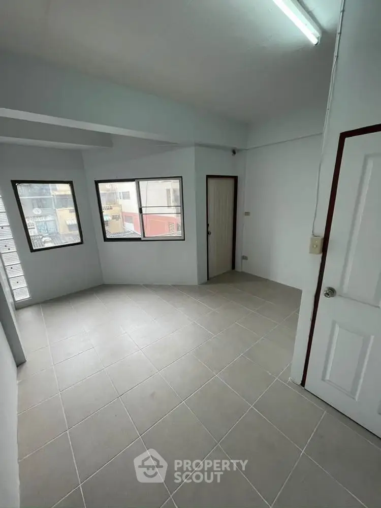 Spacious empty room with large windows and tiled flooring, ideal for customization.