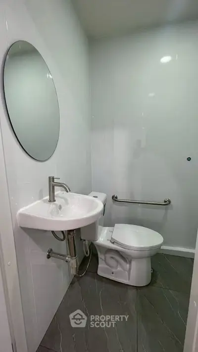 Modern minimalist bathroom with sleek fixtures and round mirror