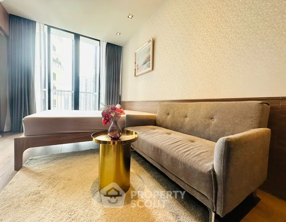 Modern bedroom with stylish sofa and elegant decor, featuring large window for natural light.