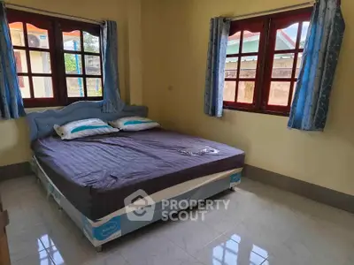 Cozy bedroom with large windows and natural light, featuring a comfortable bed and stylish curtains.