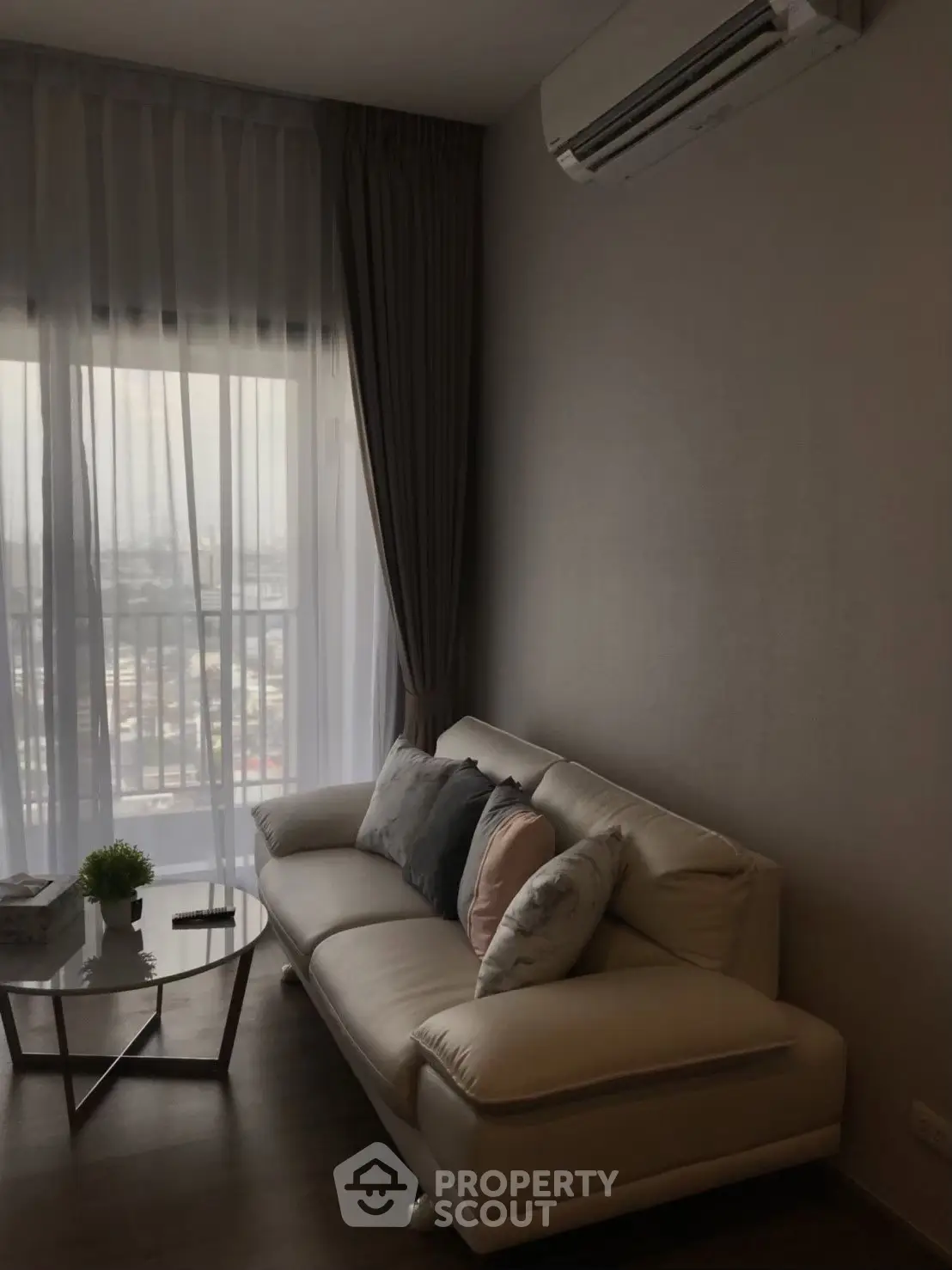 Modern living room with cozy sofa and city view through large window.