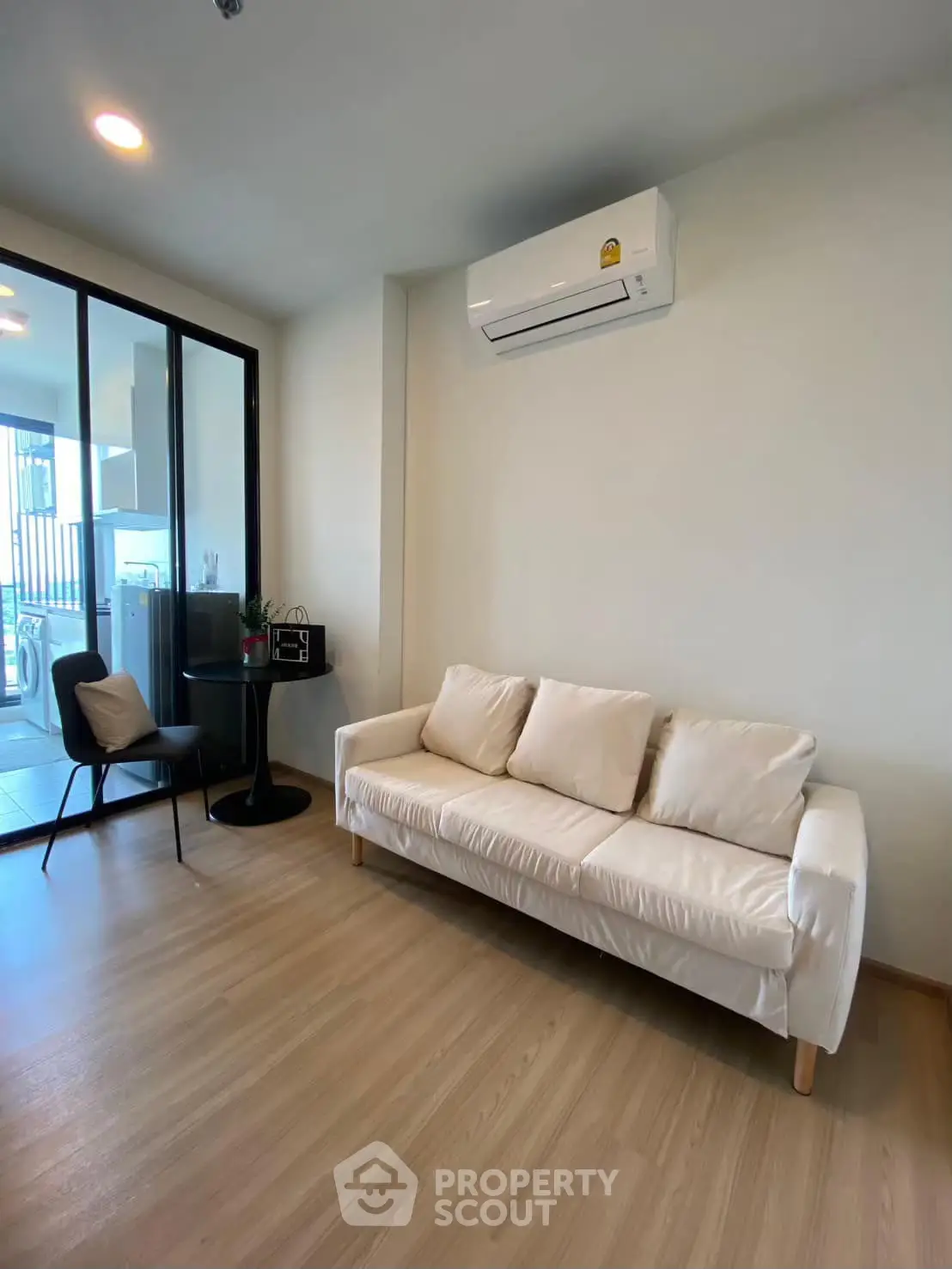 Modern living room with sleek design and air conditioning, featuring a cozy white sofa and stylish decor.