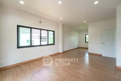 Spacious empty room with wooden flooring and large windows in modern home