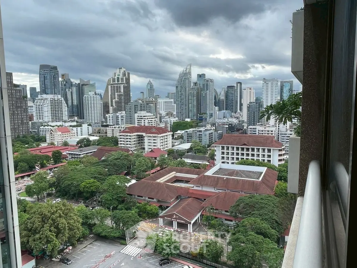 Stunning cityscape view from high-rise balcony overlooking urban skyline and lush greenery.