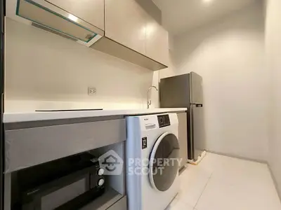 Modern kitchen with washing machine, microwave, and sleek cabinetry