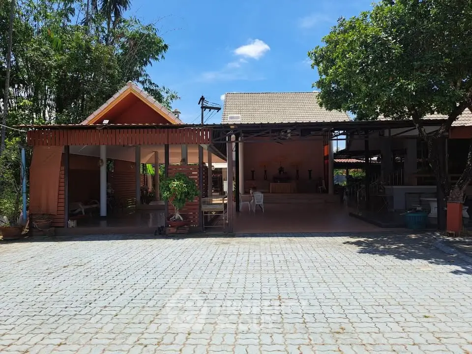 Charming outdoor view of a spacious property with a tiled courtyard and lush greenery.