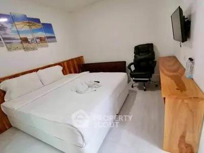 Cozy bedroom with modern decor, featuring a comfortable bed, stylish chair, and wall-mounted TV.