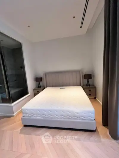 Spacious bedroom with modern design and large bed, featuring elegant lighting and parquet flooring.